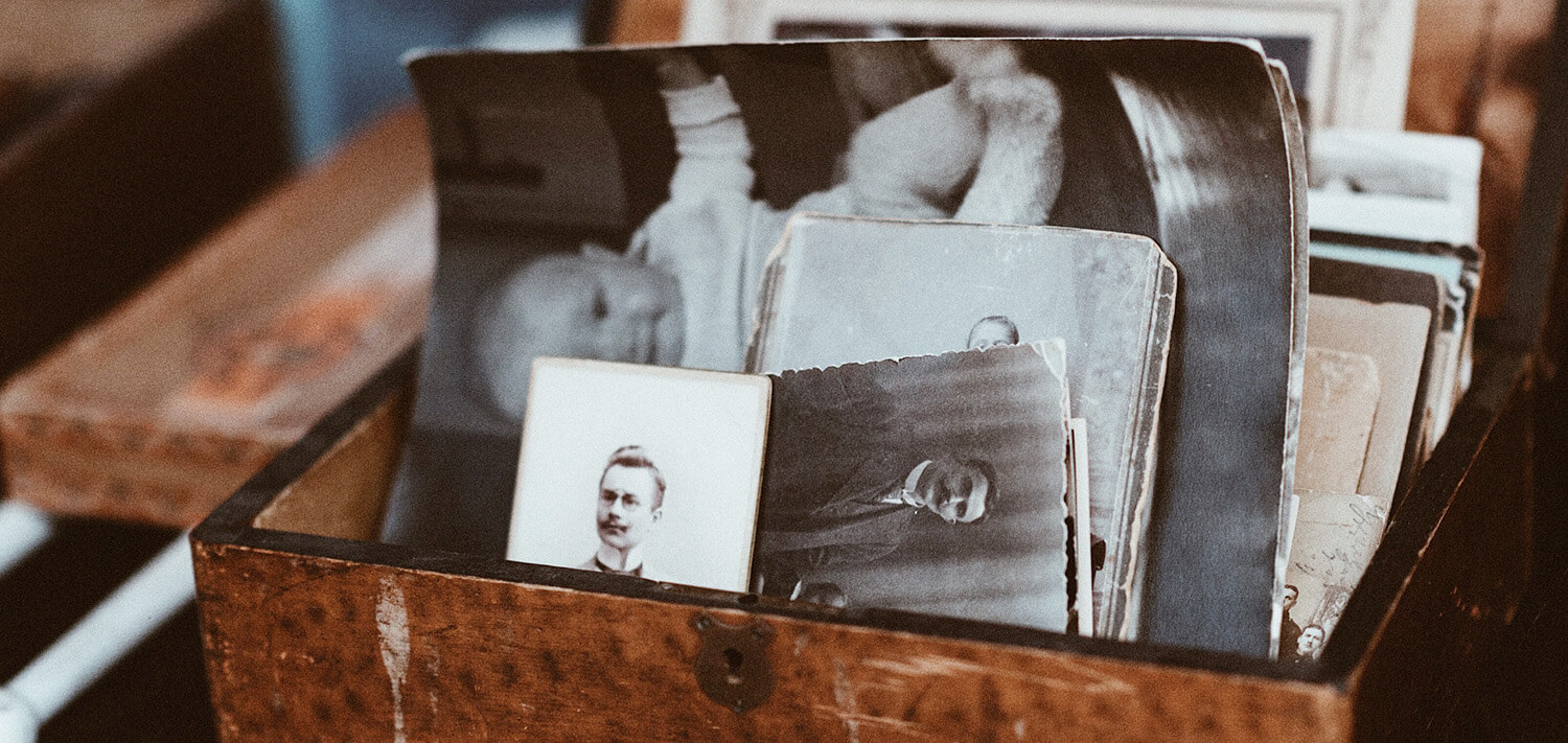 An old wooden box containing a collection of old black and white photos taken at various stages of life.